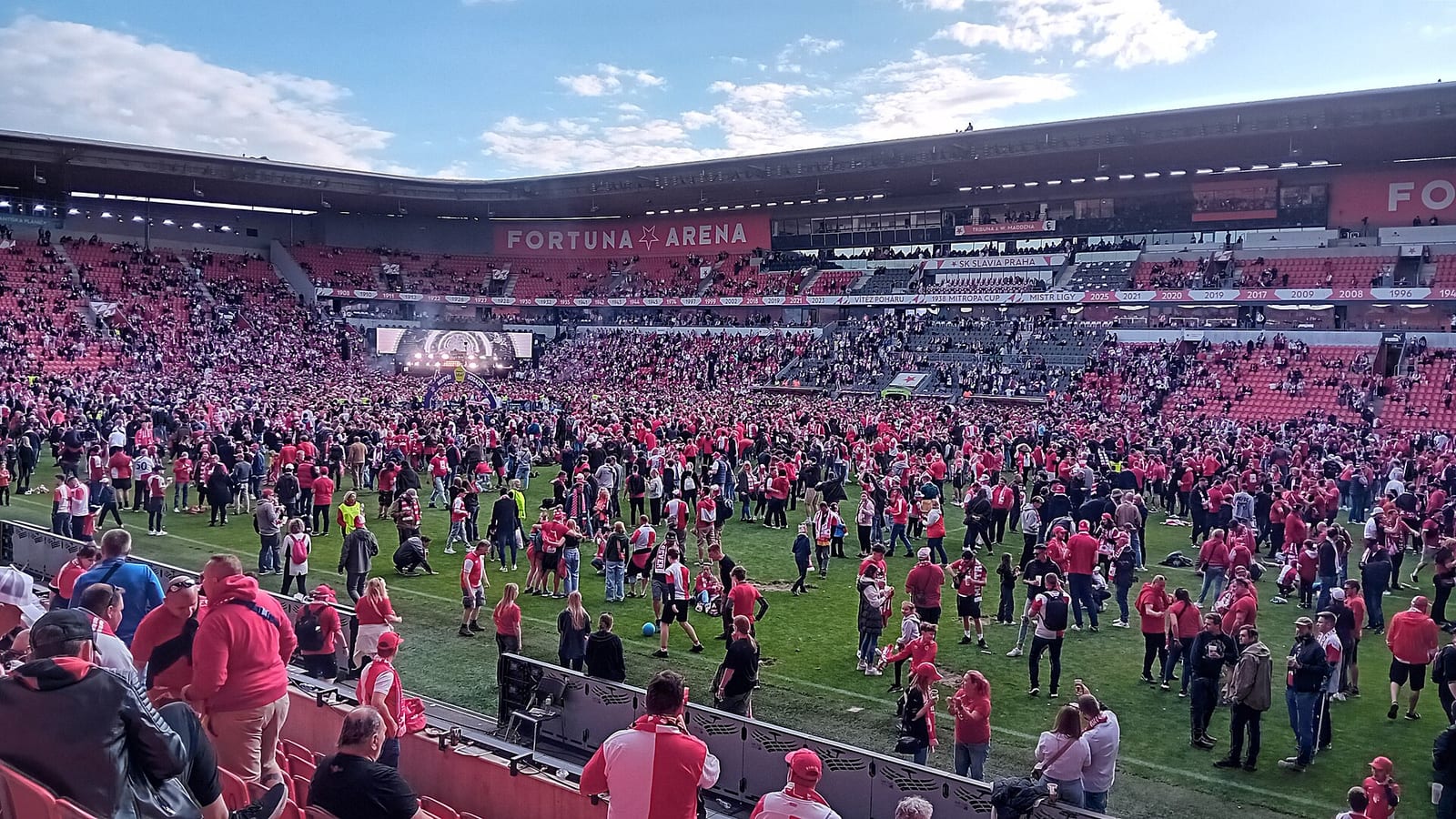 Inside the Fortuna Arena in Prague, Slavia supporters in red and white on the pitch below stands marked Fortuna Arena